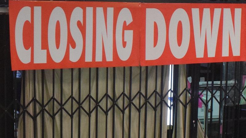 An image of a sign reading closing down and shutters on a shop