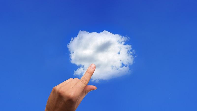 An image of a hand reaching out to touch a cloud against a blue-sky background
