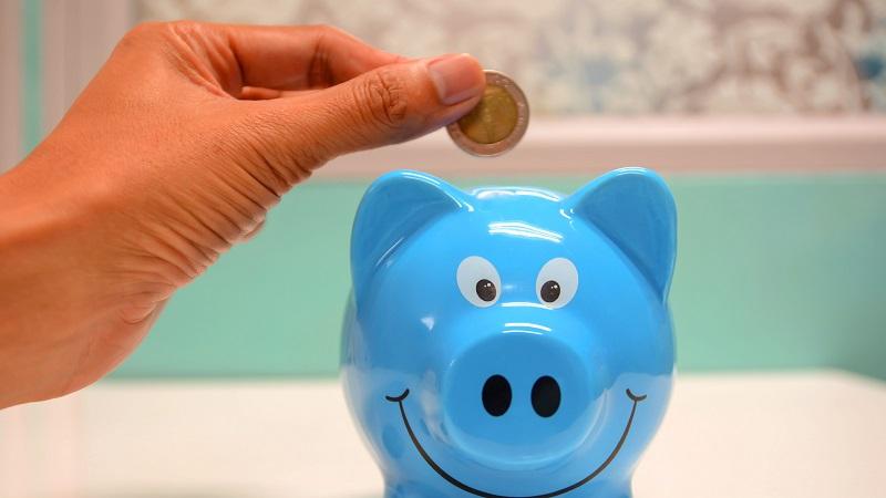 An image of coin being placed in a piggy bank