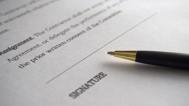 A close-up image of a pen and a contract awaiting signature