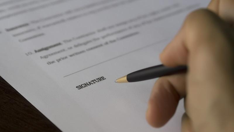 A close-up image of a pen about to sign a contract document