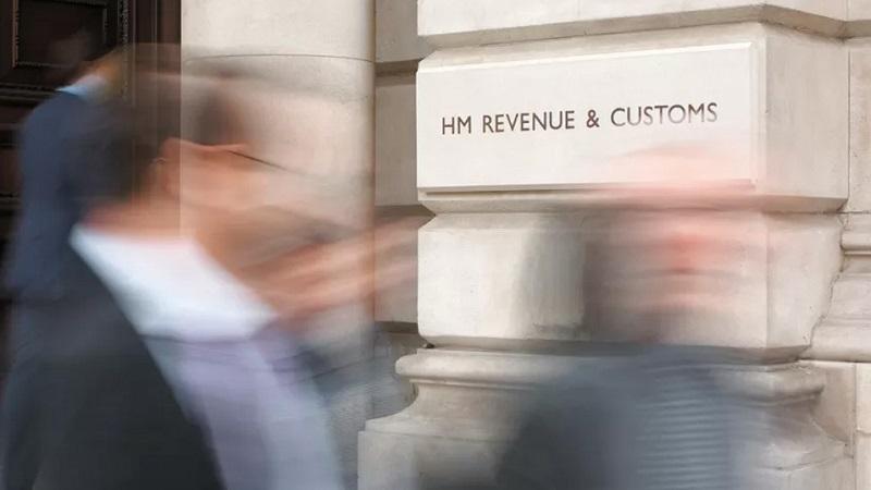 An image of blurry figures milling around in front of an HMRC