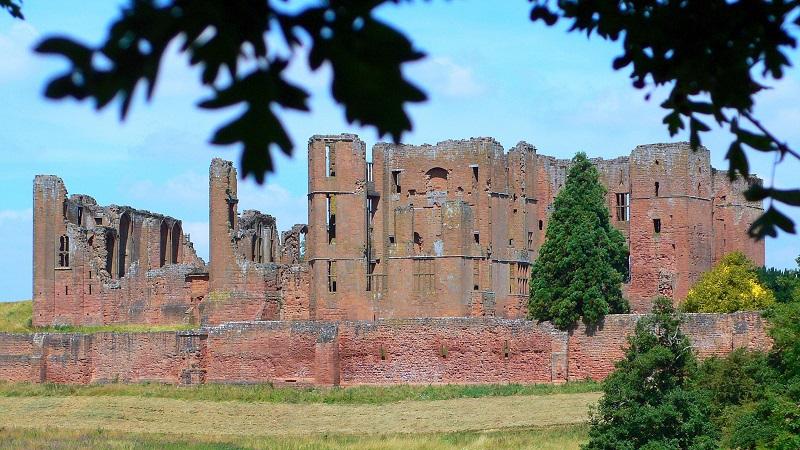 An image of Kenilworth Castle in Warwickshire glimpsed through trees