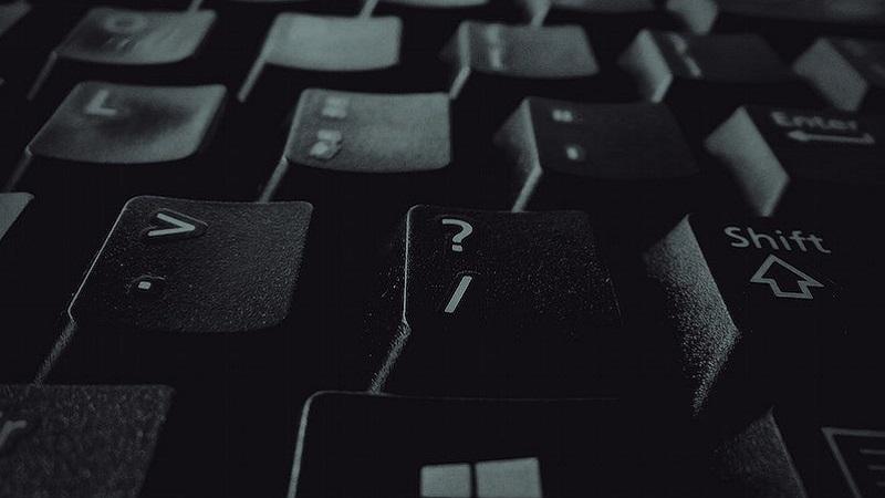 An image of a computer keyboard with the question mark key in the foreground