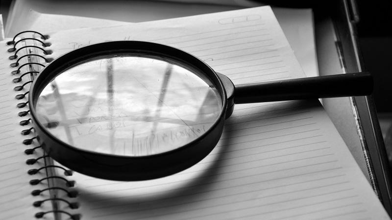 An image of a magnifying glass perched on top of a paper document