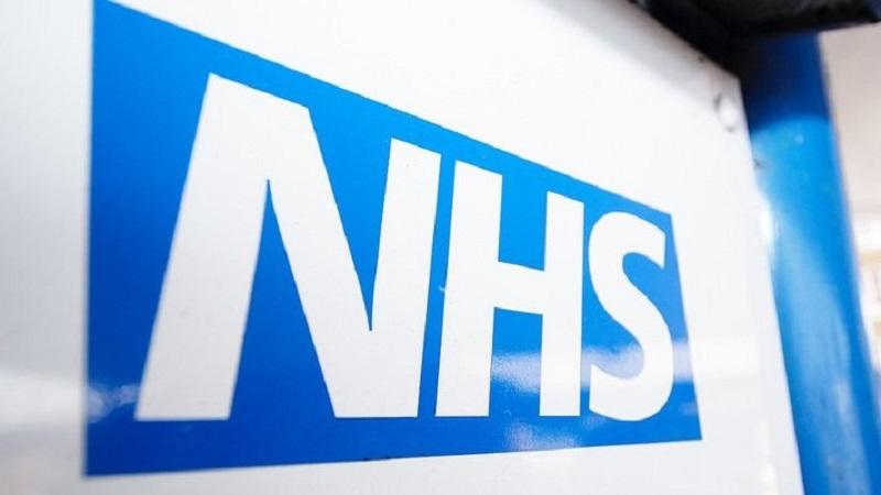 A close-up image of the NHS logo displayed on a sign