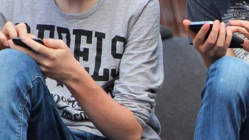 A close-up image of two people using mobile phone handsets
