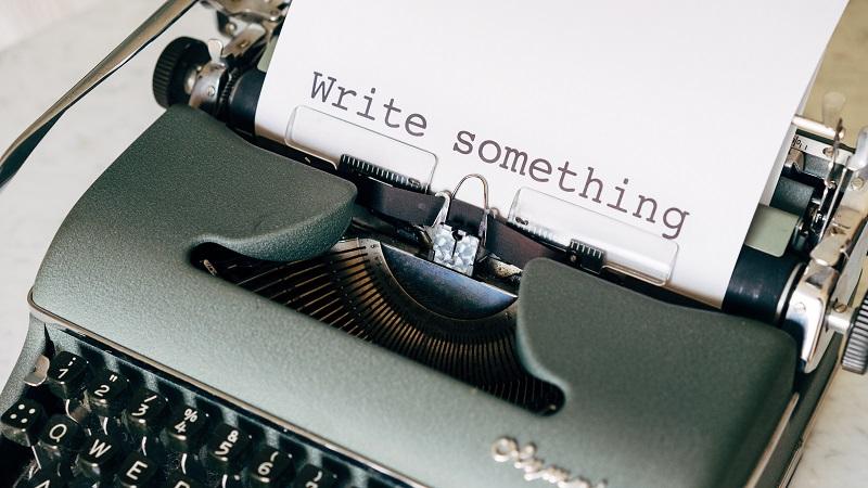 An image of typewriter with a piece of paper reading &#039;Write something&#039;